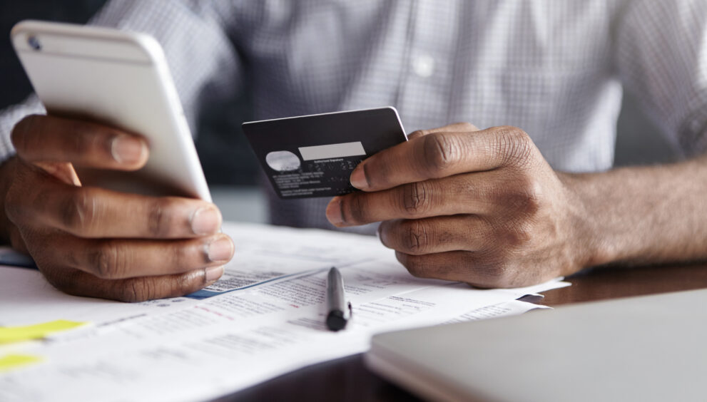 african man shirt paying goods internet using credit card cell phone